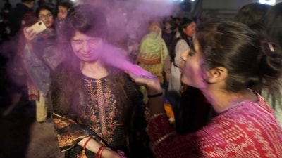 A girl from the Pakistani Hindu community blows color to the face of her friend to celebrate the Holi Festival, in Karachi, Pakistan. (AP)