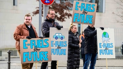 People display placards promoting so-called e-fuels (electricity made from renewable energies used for cars). (AFP) People display placards promoting so-called e-fuels (electricity made from renewable energies used for cars). (AFP)