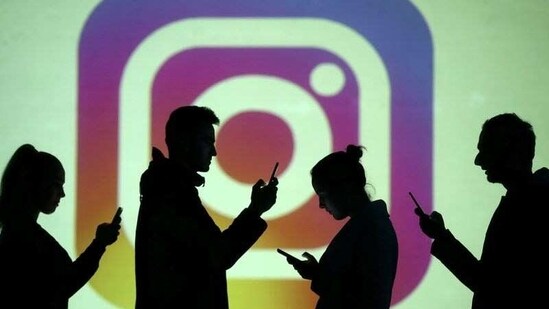 Silhouettes of mobile users are seen next to a screen projection of Instagram logo in this picture illustration. (REUTERS)