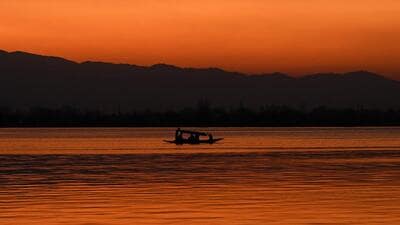 A man steers his boat in Dal Lake during sunset in Srinagar on Thursday. (AFP) A man steers his boat in Dal Lake during sunset in Srinagar on Thursday. (AFP)
