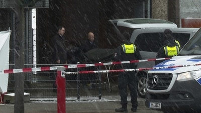 Morticians bring a covered stretcher to their vehicle at a building used by Jehovah's Witnesses in Hamburg, Germany Friday. (AP)