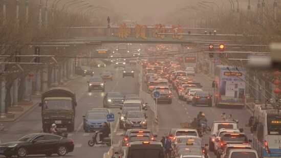 Cars and pedestrians navigate along a street shrouded in dust and haze in Beijing. China has been promoting coal-fired power, setting back efforts to cut climate-changing carbon emissions from the biggest global source. The country is also a top producer and consumer of coal and the biggest source of air pollution and climate-changing gasses, reported AP.(Mark Schiefelbein / AP)