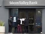 People look at signs posted outside of an entrance to Silicon Valley Bank in Santa Clara.