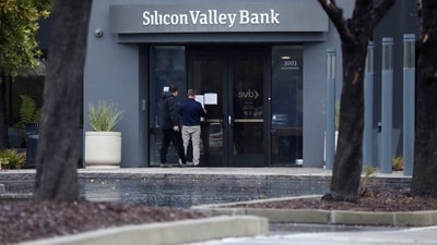 A man puts a sign on the door of the Silicon Valley Bank as an onlooker watches at the bank’s headquarters in Santa Clara, California (REUTERS)