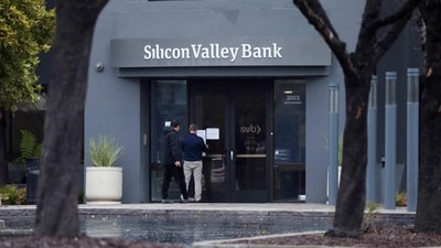 A man puts a sign on the door of the Silicon Valley Bank as an onlooker watches at the bank’s headquarters in Santa Clara, California (REUTERS)