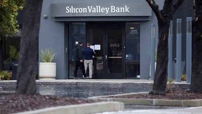 A man puts a sign on the door of the Silicon Valley Bank as an onlooker watches at the bank’s headquarters in Santa Clara, California (REUTERS)