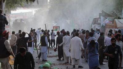 Supporters of former Pakistani Prime Minister Imran Khan stand amid the smokes of tear gas fired by police during clashes ahead of Khan's possible arrest outside his home, in Lahore, Pakistan on March 14. (REUTERS) Supporters of former Pakistani Prime Minister Imran Khan stand amid the smokes of tear gas fired by police during clashes ahead of Khan's possible arrest outside his home, in Lahore, Pakistan on March 14. (REUTERS)