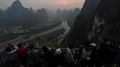 Tourists watch the sunrise at a scenic tourist spot on Xianggong Mountain, on the west bank of Li River in Yangshuo city, in southern China’s Guangxi province (AFP) Tourists watch the sunrise at a scenic tourist spot on Xianggong Mountain, on the west bank of Li River in Yangshuo city, in southern China’s Guangxi province (AFP)