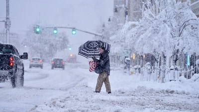 A passer-by uses an umbrella while crossing a snow-covered street, Tuesday, March 14, 2023, in Pittsfield, Mass. The New England states and parts of New York are bracing for a winter storm due to last into Wednesday. (Ben Garver/The Berkshire Eagle via AP) (AP) A passer-by uses an umbrella while crossing a snow-covered street, Tuesday, March 14, 2023, in Pittsfield, Mass. The New England states and parts of New York are bracing for a winter storm due to last into Wednesday. (Ben Garver/The Berkshire Eagle via AP) (AP)