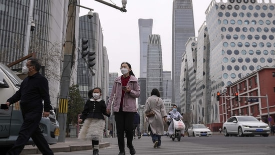 China Resumes Issuing Visas: Pedestrian and motorists cross a traffic intersection near the Central Business District in Beijing. (AP)