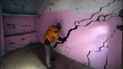 A resident shows multiple cracks in the walls of his house in Joshimath. (AP Photo)