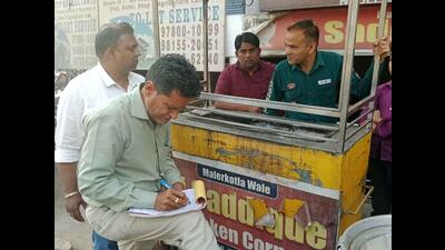 Ludhiana MC officials issuing a challan to a shopkeeper in Ludhiana on Wednesday. (HT Photo)