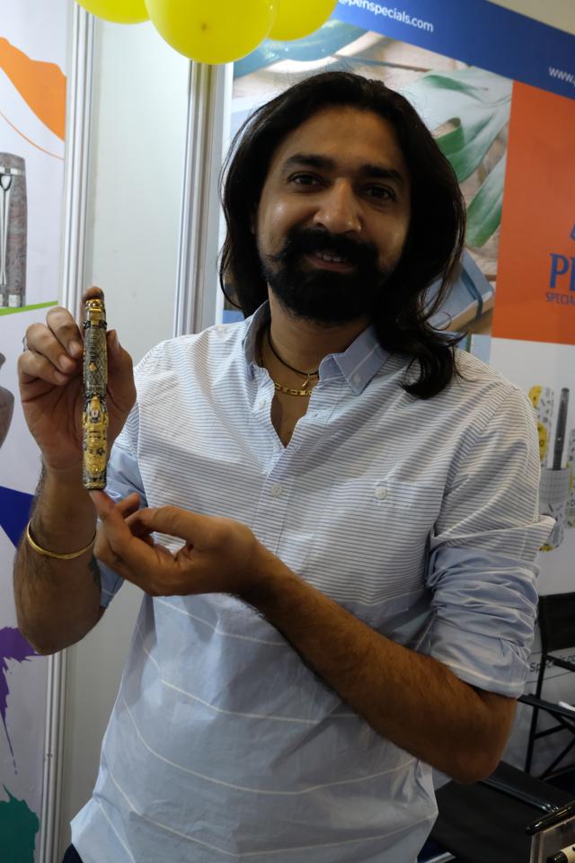 Hardik Kanakhara holds up a premium pen engraved with motifs holy to Hinduism at the stall of his family’s company, Magna Carta Pens. The pen is made of brass and weighs about 170 grams. Like other manufacturers, Magna Carta uses other materials like acrylic, ebonite (hard rubber), titanium, and gold. They have plans to use stone too. (Suhit Bombaywala) Hardik Kanakhara holds up a premium pen engraved with motifs holy to Hinduism at the stall of his family’s company, Magna Carta Pens. The pen is made of brass and weighs about 170 grams. Like other manufacturers, Magna Carta uses other materials like acrylic, ebonite (hard rubber), titanium, and gold. They have plans to use stone too. (Suhit Bombaywala)
