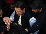 Security personnel escort former Pakistan's Prime Minister Imran Khan as he arrives to appear at the high court in Lahore on Friday.