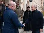 Russian President Vladimir Putin (R) shaking hands with Sevastopol Governor Mikhail Razvozhayev (L) as he visits a children's arts-and-crafts centre, part of Chersonesos Taurica historical and archeological park on the 9th anniversary of the referendum on the state status of Crimea and Sevastopol and its reunification with Russia. 