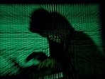 FILE PHOTO: A hooded man holds a laptop computer as cyber code is projected on him in this illustration picture taken on May 13, 2017. Top U.S. fuel pipeline operator Colonial Pipeline has shut its entire network after a cyber attack, the company said on Friday. REUTERS/Kacper Pempel/Illustration/File Photo