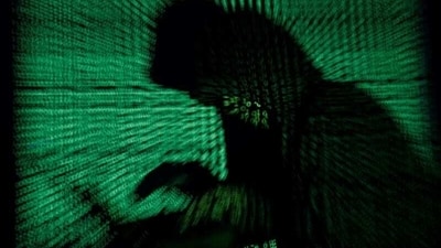FILE PHOTO: A hooded man holds a laptop computer as cyber code is projected on him in this illustration picture taken on May 13, 2017. Top U.S. fuel pipeline operator Colonial Pipeline has shut its entire network after a cyber attack, the company said on Friday. REUTERS/Kacper Pempel/Illustration/File Photo (REUTERS)