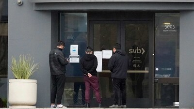 People look at signs posted outside of an entrance to Silicon Valley Bank in Santa Clara, California. (AP)