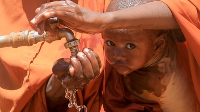 Fadumo Isaq Abdi, an internally displaced Somali woman, holds her child Maria Mohamed Ali as they drink water outside the feeding centre, a new site for IDPs, in Barwaaqo, near Baidoa, Somalia. (REUTERS)