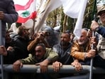Retired members of the Lebanese security and other protesters try to remove a gate in order to advance towards the government building, background, during a protest demanding better pay in Beirut, Lebanon, Wednesday. 