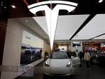 Visitors check a Tesla Model 3 car next to a Model Y displayed at a showroom of the U.S. electric vehicle (EV) maker in Beijing, China.