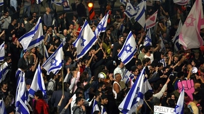 Protesters block a road and hold national flags during a rally against the Israeli government's judicial reform in Tel Aviv, Israel on March 27, 2023. - (Photo by AHMAD GHARABLI / AFP) (AFP) Protesters block a road and hold national flags during a rally against the Israeli government's judicial reform in Tel Aviv, Israel on March 27, 2023. - (Photo by AHMAD GHARABLI / AFP) (AFP)