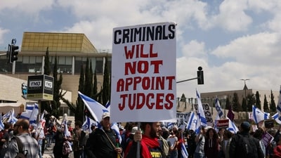 Protesters hold up Israeli flags and placards as they gather outside Israel's parliament, the Knesset, ahead of mass demonstrations in Jerusalem, on March 27. Israeli media speculated that Netanyahu may temporarily back down from the judicial reforms, with Economy Minister Nir Barkat tweeting for ministers to "unite behind the prime minister and support him in pausing the legislation". (Hazem Bader / AFP) Protesters hold up Israeli flags and placards as they gather outside Israel's parliament, the Knesset, ahead of mass demonstrations in Jerusalem, on March 27. Israeli media speculated that Netanyahu may temporarily back down from the judicial reforms, with Economy Minister Nir Barkat tweeting for ministers to "unite behind the prime minister and support him in pausing the legislation". (Hazem Bader / AFP)
