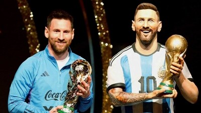 Argentina's Lionel Messi poses with a statue of himself holding the World Cup during the Conmebol event. (REUTERS)