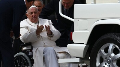 Pope Francis speaks with his aides prior to being helped get up the popemobile car from his wheelchair, as he leaves on March 29, 2023 at the end of the weekly general audience at St. Peter's square in The Vatican. (AFP) Pope Francis speaks with his aides prior to being helped get up the popemobile car from his wheelchair, as he leaves on March 29, 2023 at the end of the weekly general audience at St. Peter's square in The Vatican. (AFP)