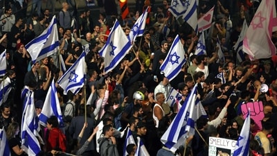 Protesters block a road and hold national flags during a rally against the Israeli government's judicial reform in Tel Aviv, Israel on March 27, 2023. (Photo by AHMAD GHARABLI / AFP) (AFP) Protesters block a road and hold national flags during a rally against the Israeli government's judicial reform in Tel Aviv, Israel on March 27, 2023. (Photo by AHMAD GHARABLI / AFP) (AFP)