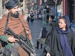 Taliban In Afghanistan: A Taliban fighter stands guard as a woman walks past in Kabul, Afghanistan. Taliban In Afghanistan: A Taliban fighter stands guard as a woman walks past in Kabul, Afghanistan.