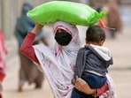 A woman carries her child while she leaves with a free bag of flour from a government distribution point in Islamabad on April 1. 
