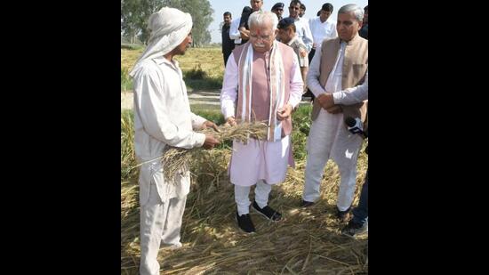 Haryana chief minister Manohar Lal Khattar interacting with a farmer while assessing damage to wheat crop at Tigrana village in Bawani Khera constituency of Bhiwani district on Monday. State agriculture minister JP Dalal is also seen. (HT Photo)