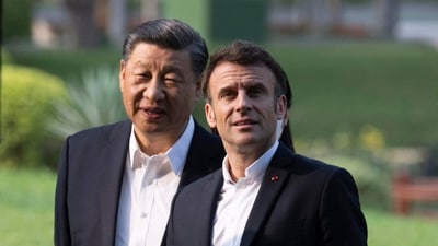 Chinese President Xi Jinping and French President Emmanuel Macron walk in the garden of the Guandong province governor's residence, in Guangzhou, China, Friday. (AP)