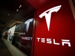 A sign bearing the Tesla company logo is displayed outside a Tesla store.