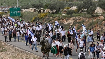 Israeli settlers march towards the outpost of Eviatar, near the Palestinian village of Beita, situated in southern Nablus in the occupied West Bank, on April 10. ( Gil Cohen-Magen / AFP) Israeli settlers march towards the outpost of Eviatar, near the Palestinian village of Beita, situated in southern Nablus in the occupied West Bank, on April 10. ( Gil Cohen-Magen / AFP)
