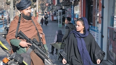 Taliban In Afghanistan: A Taliban fighter stands guard as a woman walks past in Kabul, Afghanistan. Taliban In Afghanistan: A Taliban fighter stands guard as a woman walks past in Kabul, Afghanistan.