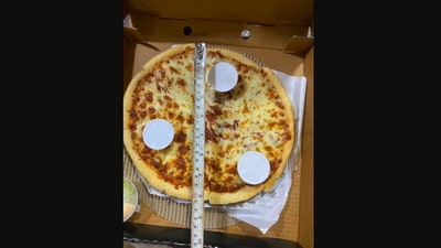 The woman shared this picture of someone measuring a pizza with a measuring tape. (Twitter/@shubhibhatia03)