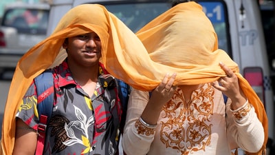 Pedestrians can be seen covering themselves with a scarf to protect themselves from the scorching sun as they walk on a city street during a hot summer day in Kolkata. (PTI)