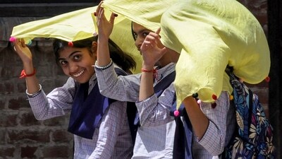 Students use a scarf to shield themselves from the hot summer sun, in Amritsar. (PTI)
