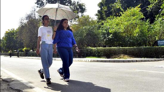 Girls walking with an umbrella to escape from the scorching heat in Ludhiana on Thursday. (HT Photo)