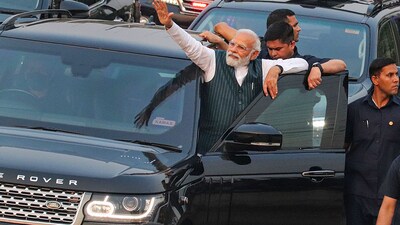 PM Modi was seen standing on the running board of his moving car and waving at an enthusiastic crowd. (ANI/PIB) PM Modi was seen standing on the running board of his moving car and waving at an enthusiastic crowd. (ANI/PIB)