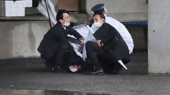 A man (bottom) is arrested after throwing what appeared to be a smoke bomb in Wakayama on April 15, 2023. ((IJI Press / AFP) / Japan OUT)