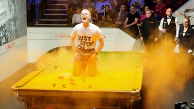 A 'Just Stop Oil' protester jumps on the table and throws orange powder during World Snooker Championship (AP)