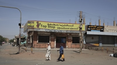 People walk past shuttered shops in Khartoum, Sudan, Tuesday, April 18, 2023. Sudan's embattled capital has awoken to a fourth day of heavy fighting between the army and a powerful rival force for control of the country. Airstrikes and shelling intensified on Monday in parts of Khartoum and the adjoining city of Omdurman. (AP) People walk past shuttered shops in Khartoum, Sudan, Tuesday, April 18, 2023. Sudan's embattled capital has awoken to a fourth day of heavy fighting between the army and a powerful rival force for control of the country. Airstrikes and shelling intensified on Monday in parts of Khartoum and the adjoining city of Omdurman. (AP)