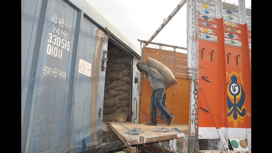 A worker transfers wheat from a truck to a railway coach in Patiala on Tuesday. (HT photo)