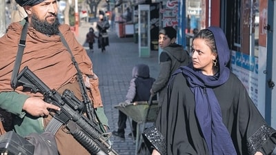 United Nations In Afghanistan: A Taliban fighter stands guard as a woman walks past in Kabul, Afghanistan. (AFP) United Nations In Afghanistan: A Taliban fighter stands guard as a woman walks past in Kabul, Afghanistan. (AFP)