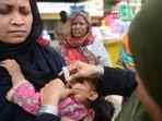 A health worker administers polio vaccine drops to a child at a railway station during a vaccination campaign in Karachi.