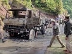 Armed security personnel walk at a site of an attack inspecting charred army vehicle after terrorists opened fire at an Indian army vehicle in Poonch.