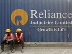 FILE PHOTO: Labourers rest in front of an advertisement of Reliance Industries Limited at a construction site in Mumbai.
